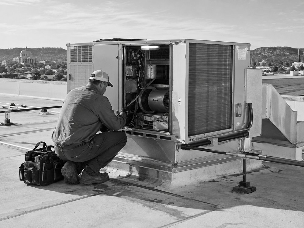 Packaged rooftop units on a low commercial building with a service hatch open